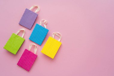 Pembe arkaplandaki küçük noktalı alışveriş çantalarının fotokopi alanı ile üst görünümü 