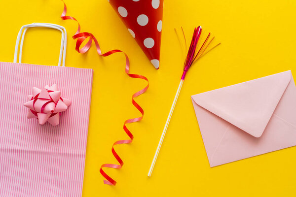 Вид сверху на кепку вечеринки возле сумки с покупками и эмблему на желтом фоне 