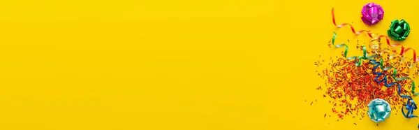 黄色の背景にスプリンクルでお祝いの蛇行とギフト弓のトップビュー バナー — ストック写真