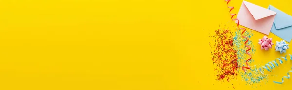 黄色の背景にスプリンクルと蛇紋岩の近くのカラフルな封筒のトップビュー バナー — ストック写真