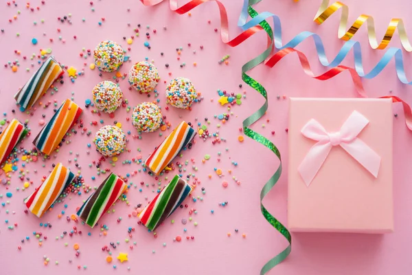 stock image Top view of gift box near serpentine and colorful candies on pink background 