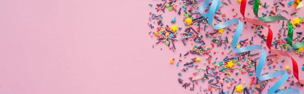 분홍빛 배경에 색깔의 스프링클러와 서펜타인의 현수막 — 스톡 사진