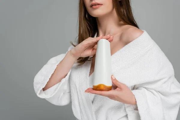 stock image partial view of young woman with shiny hair holding bottle with shampoo isolated on grey