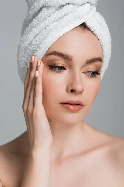 portrait of young woman with towel on head looking away isolated on grey