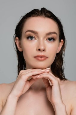 Saçları ıslak genç ve güzel bir kadının portresi. Gri renkli kameraya bakıyor. 