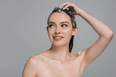 cheerful young woman washing foamy hair isolated on grey clipart