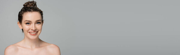веселая молодая женщина с пеной на голове улыбается изолированно на сером, баннер  
