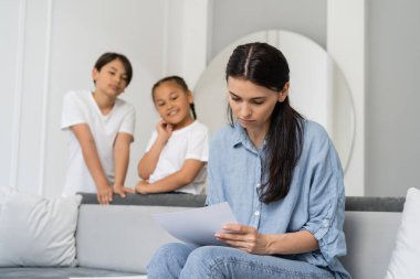 Annenin elinde bulanık Asyalı çocukların olduğu bir kağıt vardı. 