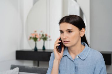 Esmer kadın evde cep telefonuyla konuşuyor. 