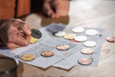 KYIV, UKRAINE - 17 Kasım 2022: Masanın yanında Bitcoin tutan olgun işadamlarının kısmi görüşü