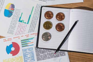 KYIV, UKRAINE - 17 Kasım 2022: Infographics yakınlarındaki defterde altın ve gümüş bitcoinlerin üst görünümü
