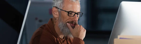オフィス バナーのコンピュータモニタを見て眼鏡の成熟したビジネスマンに焦点を当て — ストック写真