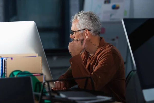 オフィスにおける電子計算機や論文の近くで働く中年のビジネスマンの側面図 — ストック写真