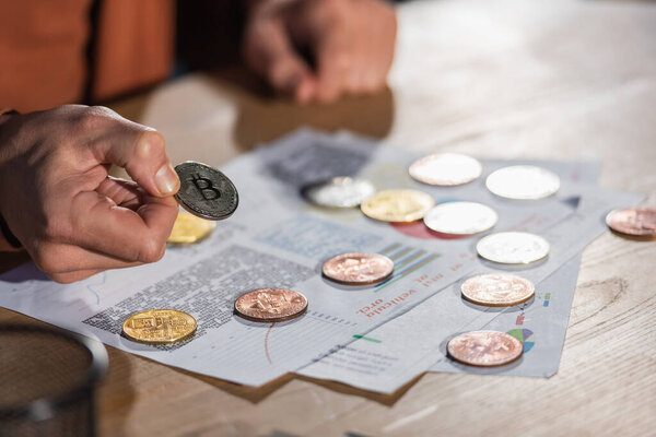 КИЕВ, УКРАИНА - 17 ноября 2022 года: частичный взгляд зрелого бизнесмена, держащего биткойн рядом с документами на столе