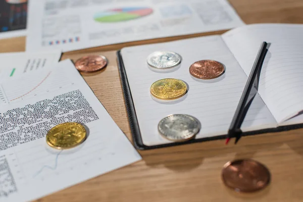 stock image KYIV, UKRAINE - NOVEMBER 17, 2022: silver and golden bitcoins on blank copybook near documents with business analytics