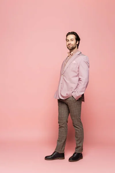 Full length of host of event looking at camera on pink background