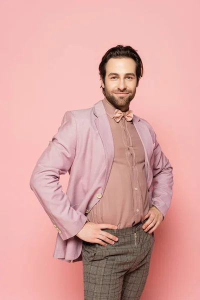 Trendy host of event posing and looking at camera on pink background