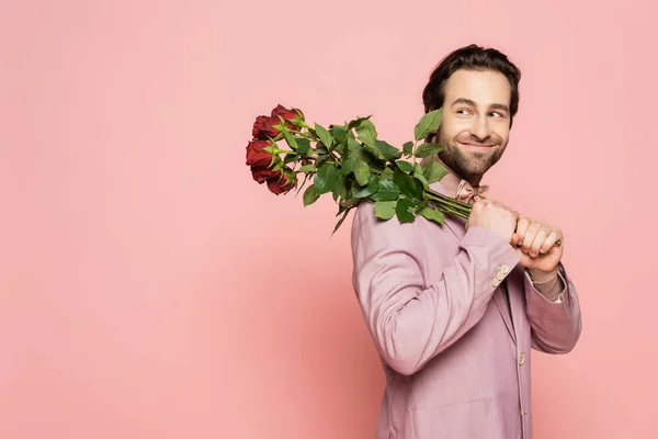 Cheerful host of event holding bouquet of flowers isolated on pink