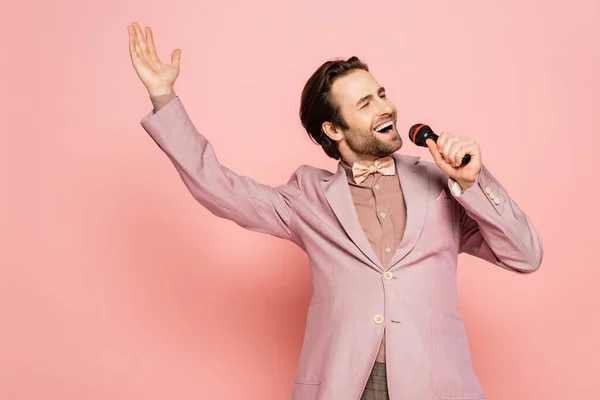 Brunette host of event singing at microphone on pink background