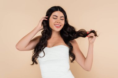 Tepedeki gülümseyen kadın bej rengi saçlara dokunuyor. 