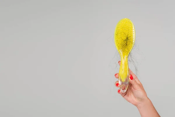 stock image cropped view of woman with red manicure holding yellow hair brush with lost hair isolated on grey