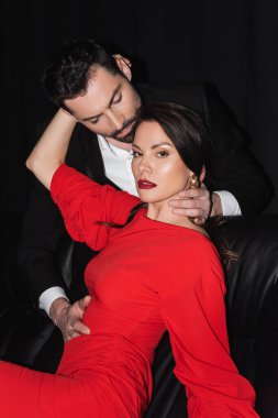 Tutkulu ve sakallı adam siyah dudaklı esmer kadına bakıyor. 