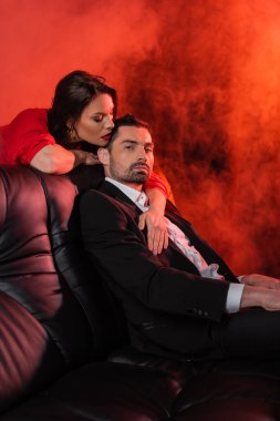 brunette woman seducing boyfriend in formal wear on red with smoke  clipart
