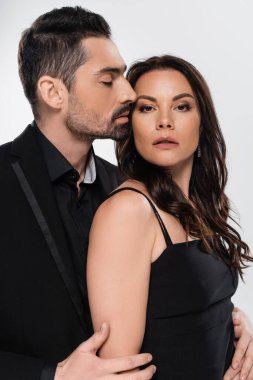 Tutkulu takım elbiseli adam gri elbiseli esmer kadını baştan çıkarıyor. 