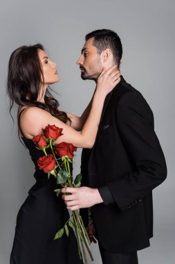 Siyah takım elbiseli sakallı bir adamın, tutkulu bir kadının yanında, gri bir elbisenin içinde kırmızı güller taşıdığını gördüm.