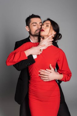 Tutkulu bir adam, gri arka planda seksi kız arkadaşının boynuna dokunuyor. 