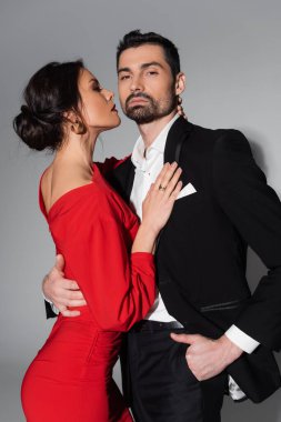 Zarif adam gri arka planda seksi kız arkadaşına poz veriyor ve sarılıyor. 