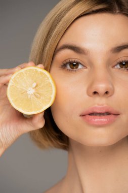 Gri renkte limon tutan genç sarışın kadın portresi 