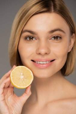 Gri üzerinde organik limon tutan mutlu genç kadın portresi 