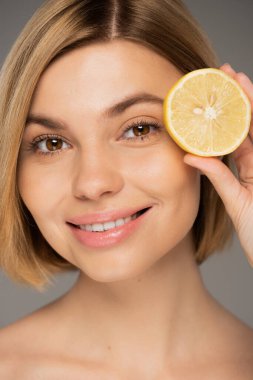 Gri üzerinde taze limon tutan mutlu genç kadın portresi 