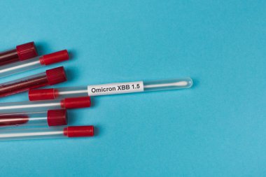 Top view of cotton swabs near test tubes with blood samples on blue background 