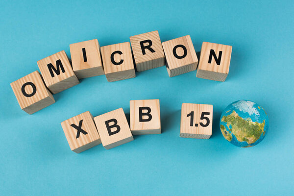 Top view of wooden cubes with omicron xbb lettering near globe on blue background 