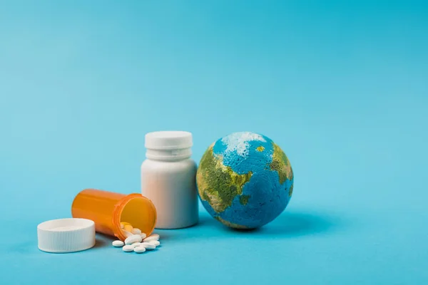 stock image Globe and jars with pills from new omicron strain on blue background 