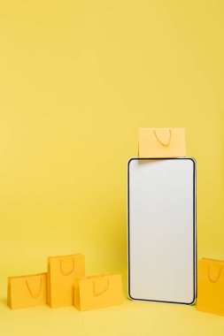 vertical view of huge mock-up of smartphone near shopping bags on yellow background