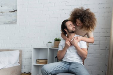 curly young woman hugging bearded man in jeans and white t-shirt 