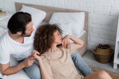 high angle view of young woman with closed eyes leaning on legs of boyfriend in jeans 