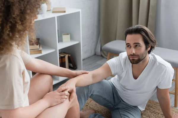 stock image curly woman sitting and touching hand of bearded boyfriend in bedroom 