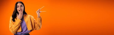 Excited young woman holding bamboo chopsticks isolated on orange, banner 