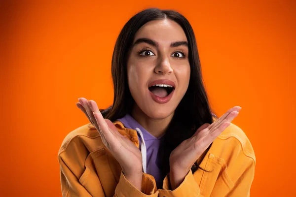 Stock image Portrait of excited brunette woman looking at camera isolated on orange