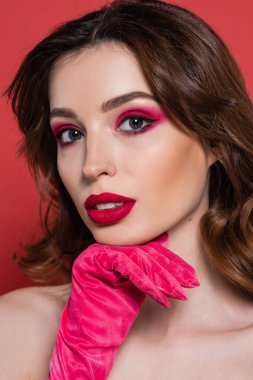 young woman with magenta color eye shadow looking at camera isolated on pink 
