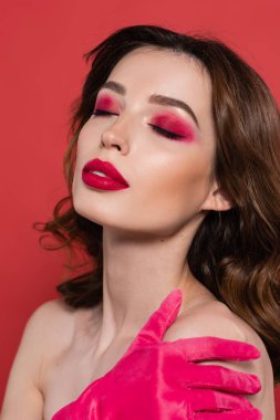portrait of young woman with magenta color eye shadow and closed eyes isolated on pink 