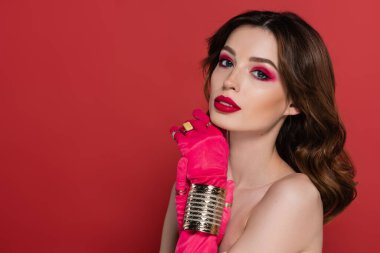 portrait of young woman with magenta color gloves with golden bracelet posing isolated on pink 
