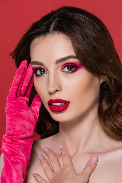 young woman with magenta color eye shadow and bright glove posing isolated on pink