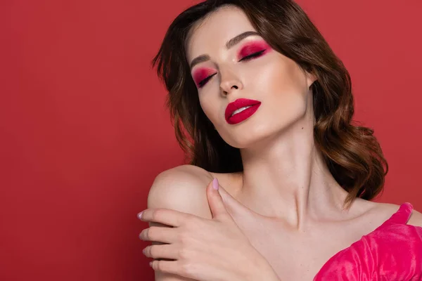 stock image portrait of young woman with magenta color eye shadow and glove embracing herself isolated on pink 