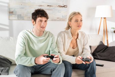 KYIV, UKRAINE - OCTOBER 24, 2022: young couple playing video game at home 