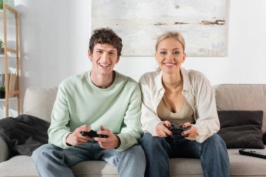 KYIV, UKRAINE - OCTOBER 24, 2022: happy young couple playing video game at home 